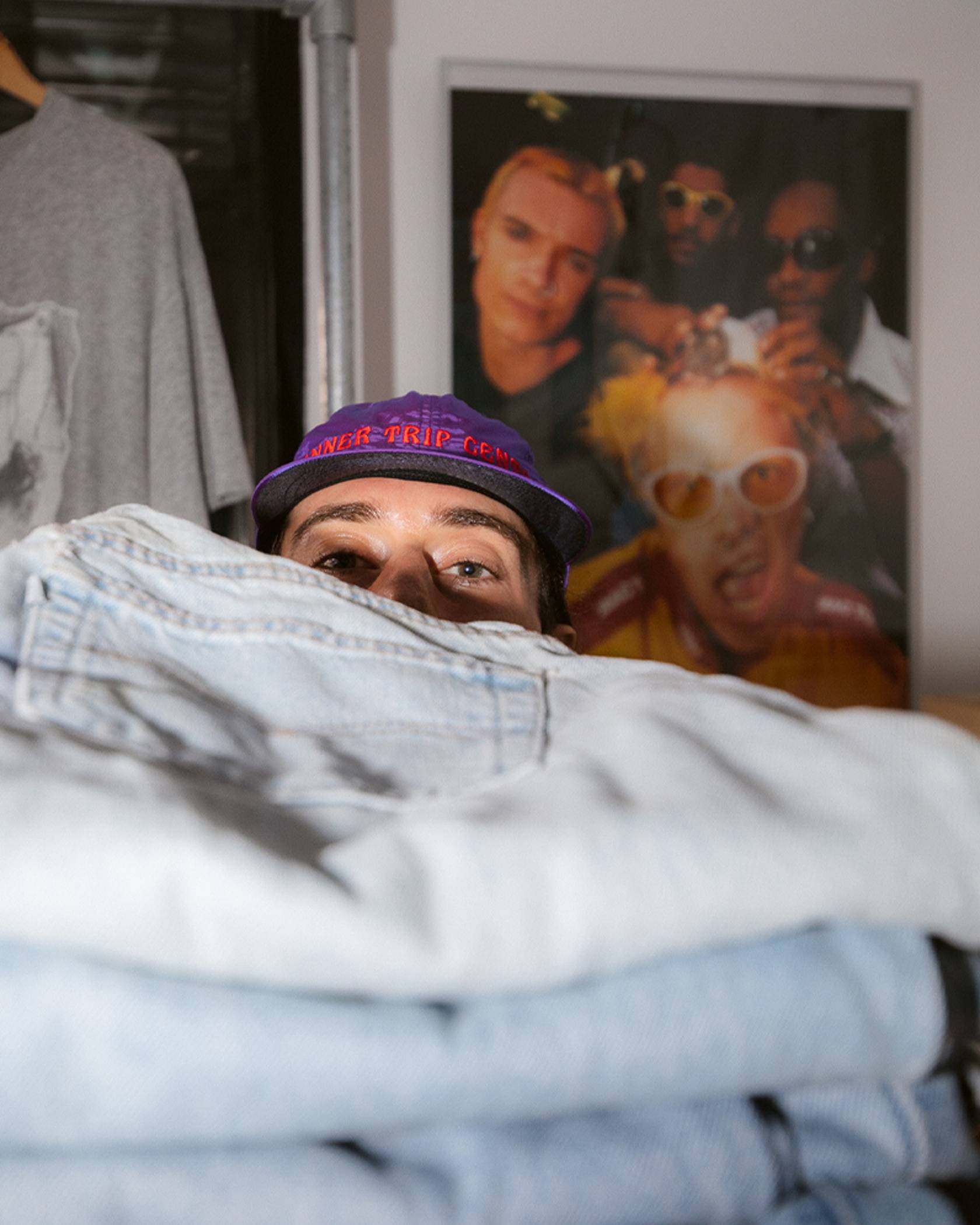 Photo of Sam Trotman peeking out from behind a stack of Levi's jeans.