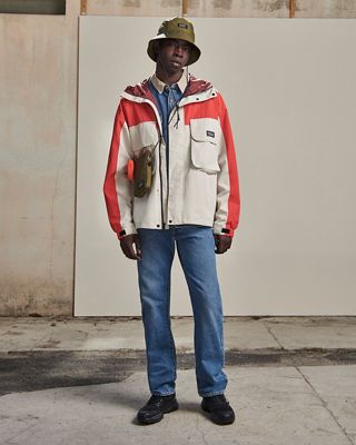 Man in mid wash blue jeans, color blocked windbreaker, denim shirt, utility cross body and bucket hat 2022_fall_outfits_for_men