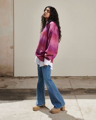 Woman outside in a fuzzy berry multi colored sweater, white button down and flare jeans 2022_fall_outfits_for_women