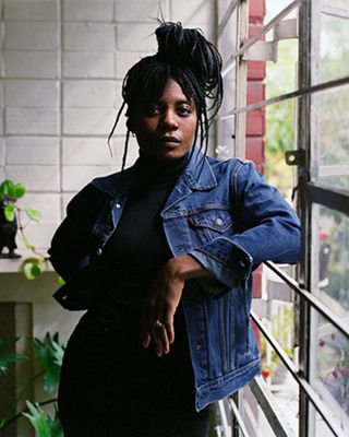 Portrait of Mennlay Golokeh Aggrey in her home with images of cannabis on either side of the portrait.