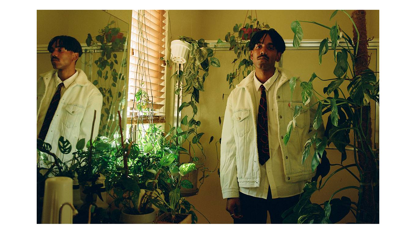 Portrait of Jerrod La Rue standing in his plant-filled bathroom.