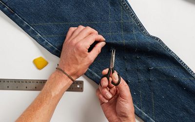 pair of jeans being cut with a scissor