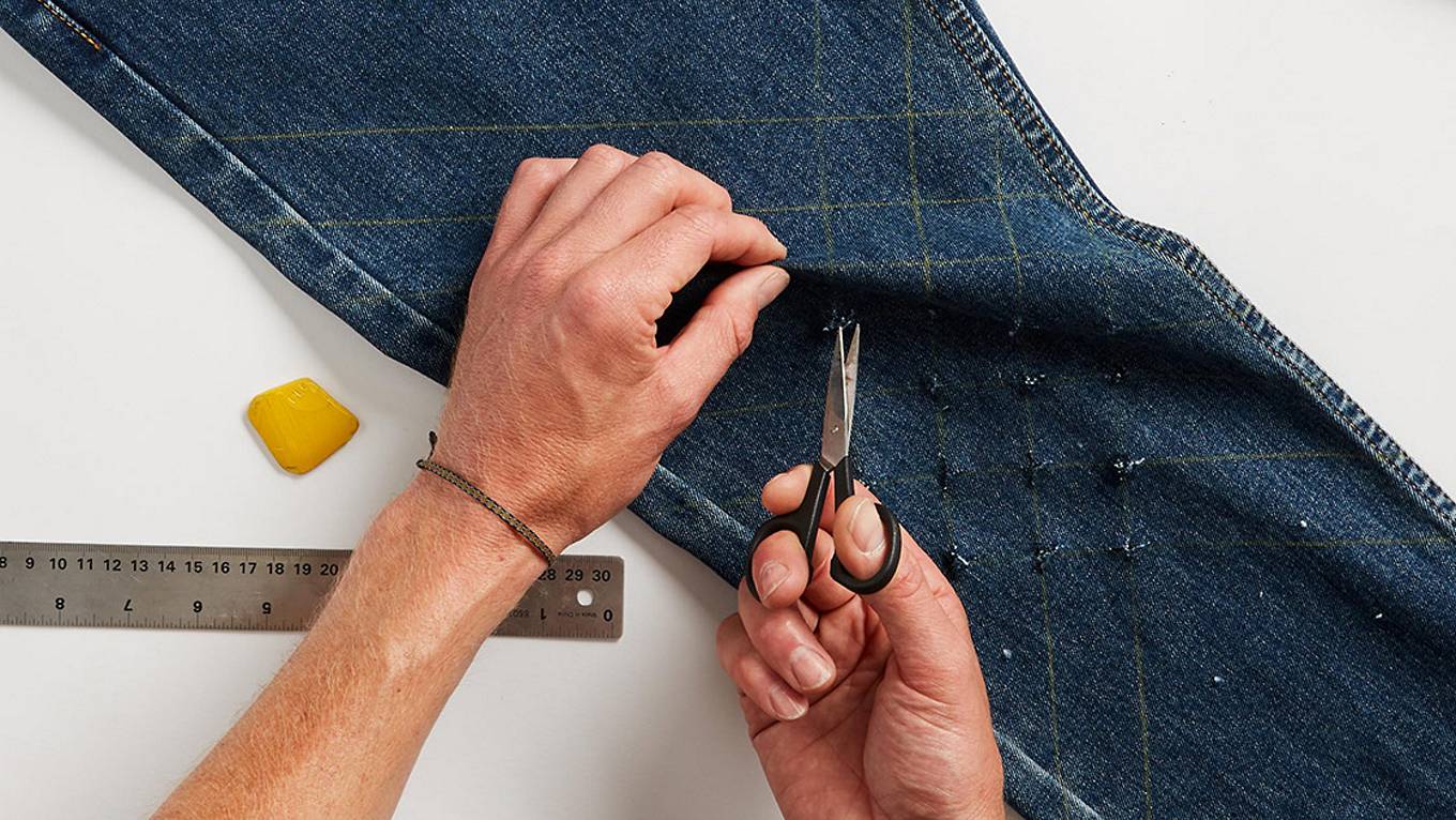 pair of jeans being cut with a scissor