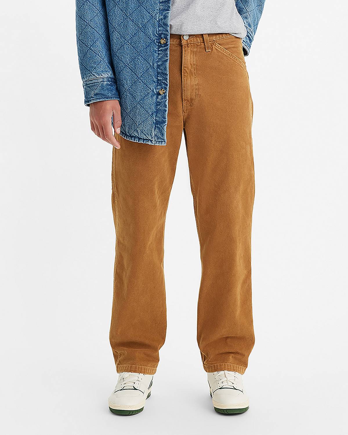 Model wearing tan relaxed fit pants.
