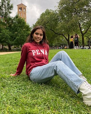 Photo of Xiye Bastia sitting in the grass on campus.