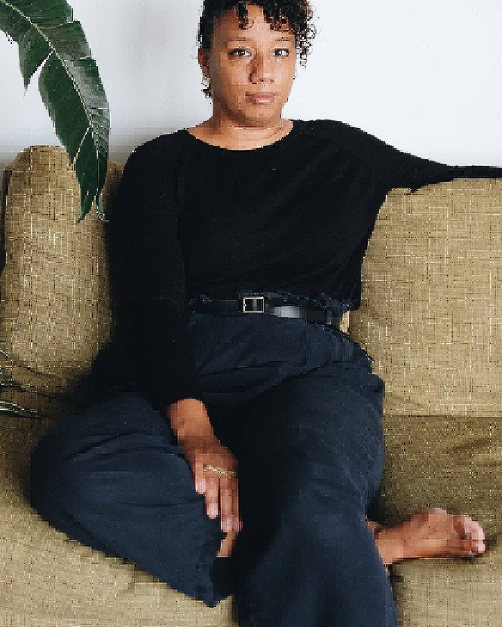 Photo of Solange Parris sitting on a couch. She is wearing all black.