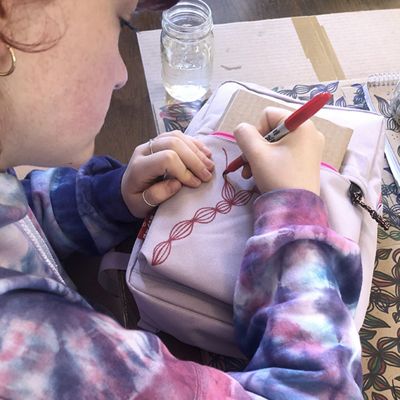girl drawing vines on backpack