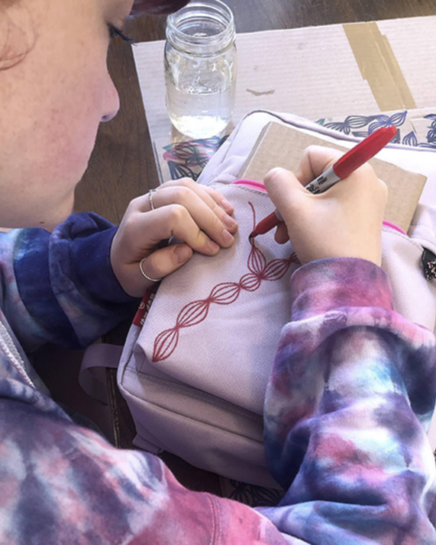 girl drawing vines on backpack