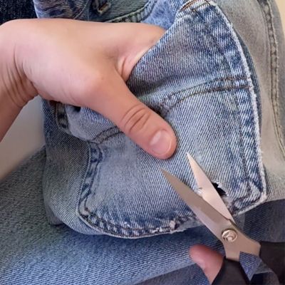 scissors trimming hole on denim jeans