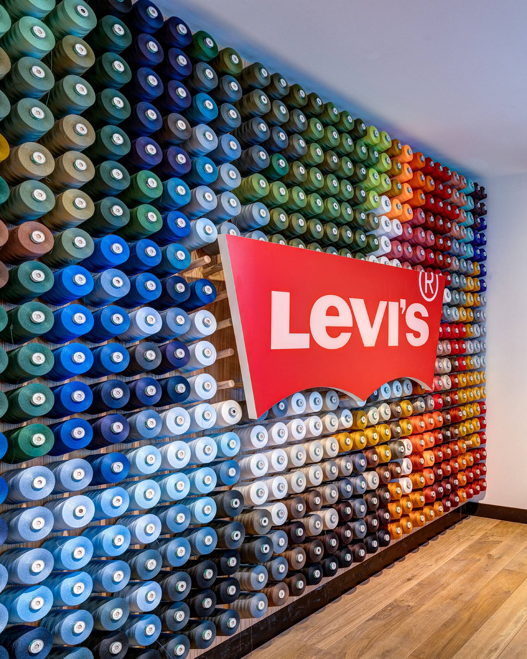 Large Levi's® Batwing Logo sign against a wall of multicolor thread