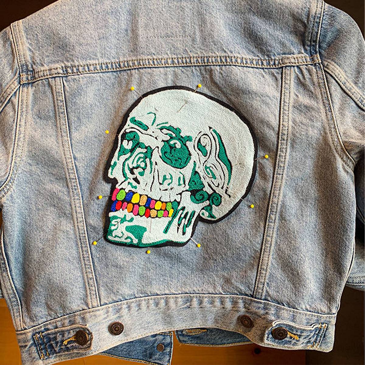 Intricate teal and seafoam green chain stitch skull embroidery on a Trucker