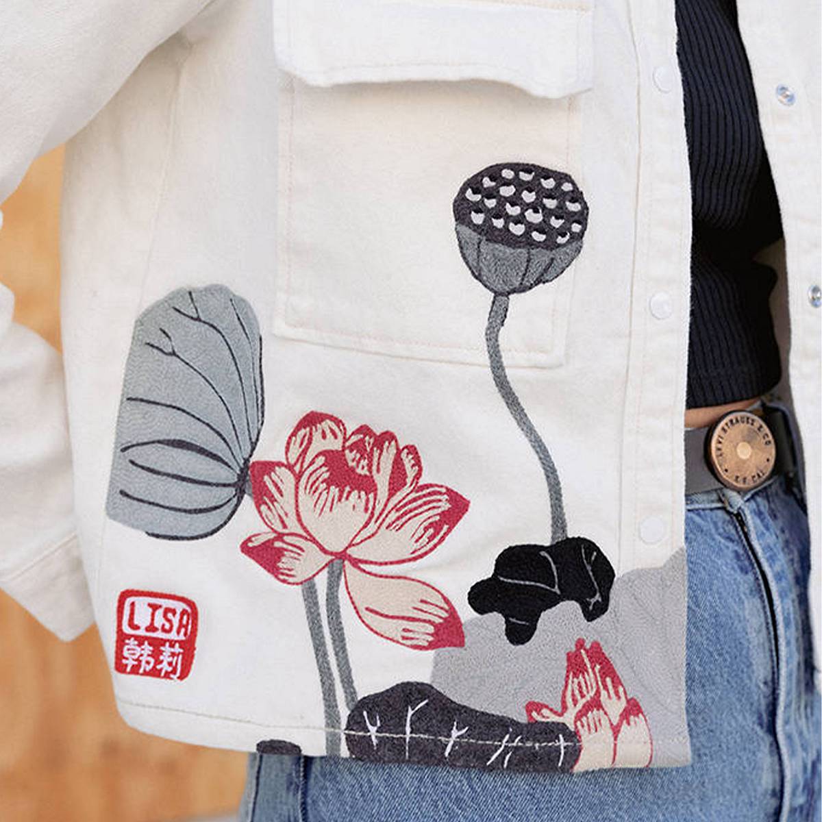 Detail shot of a white jacket with floral red, grey and black embroidery