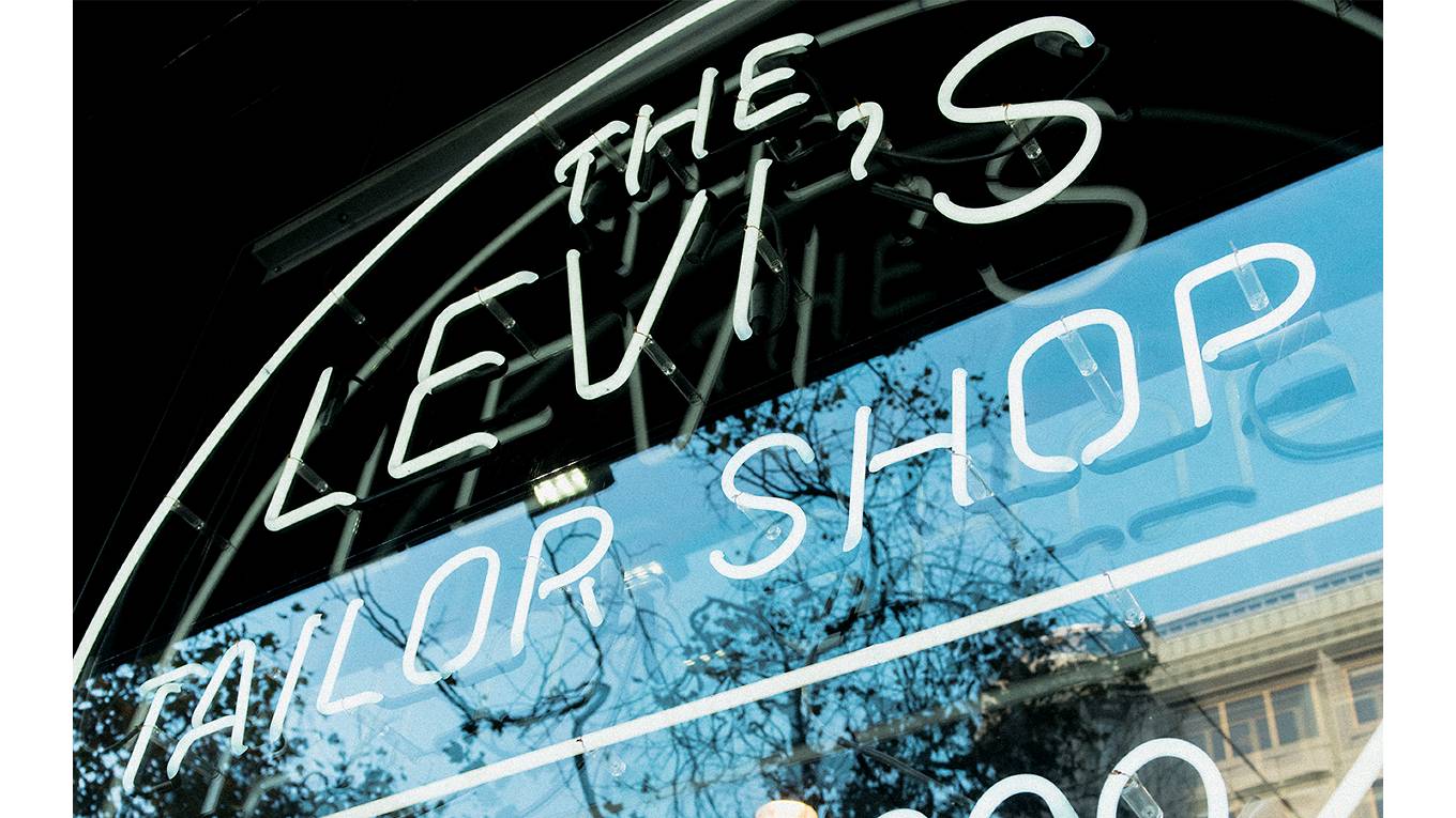 The window of a Levi's tailor shop with an electric sign saying, "The Levi's Tailor Shop"