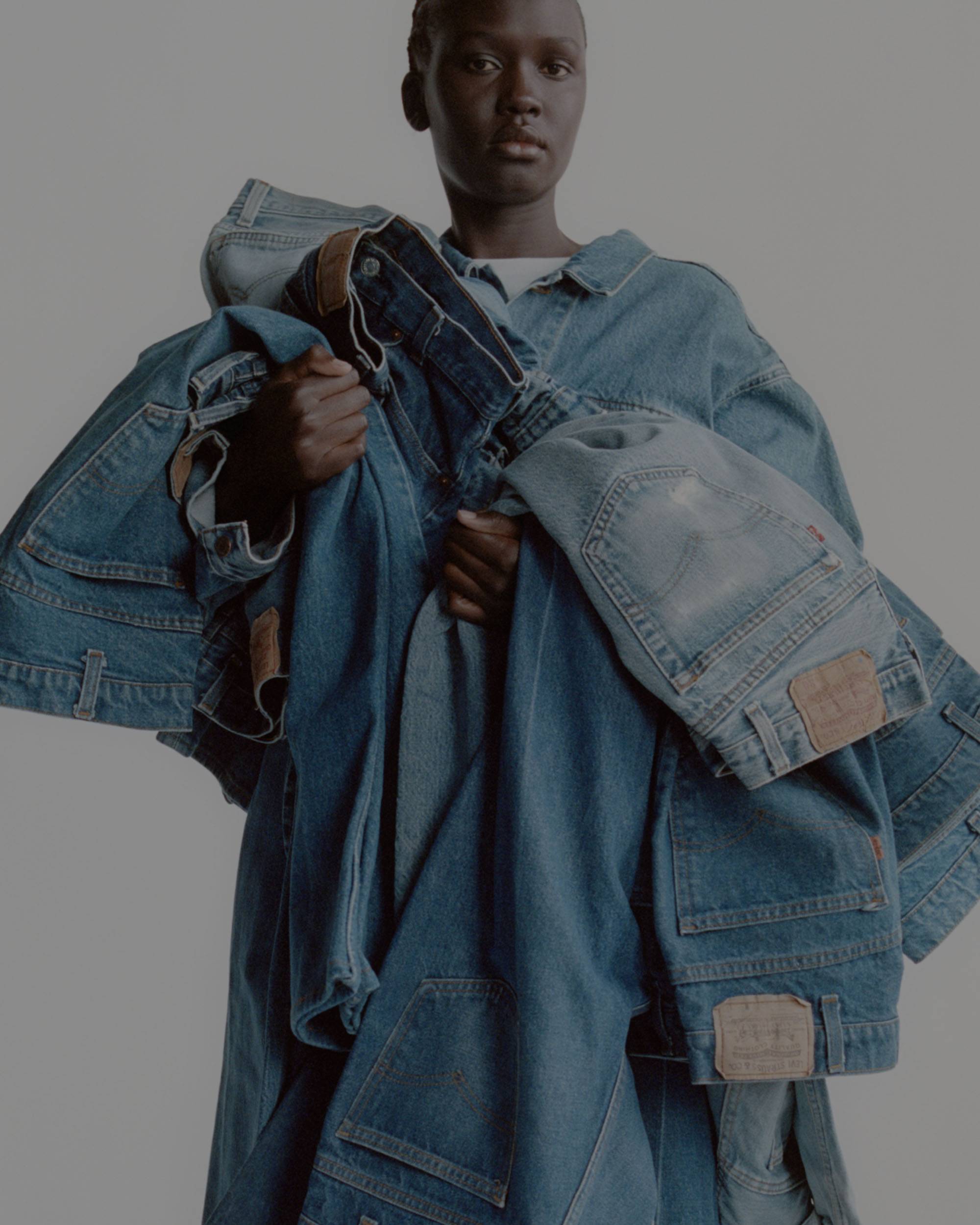 Model holding large pile of jeans