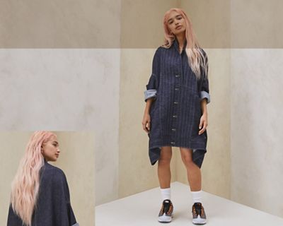 Model wearing the Levi's® Upside-Downable Trucker Jacket. The image on the right shows the back of the model and their pink hair. The image on the left shows a head-to-toe image of them in the jacket.