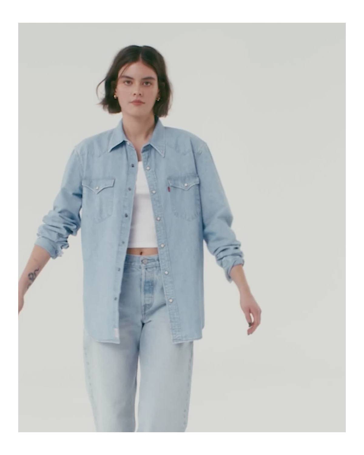 Video of model in women's light wash denim button down, light wash jeans and white tank