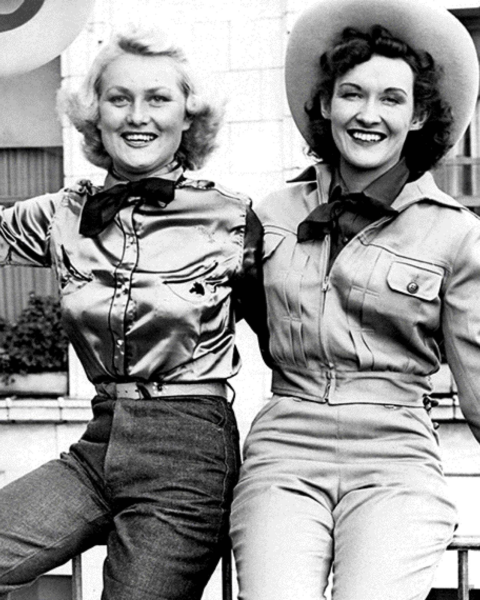 Two women sitting wearing denim jackets.