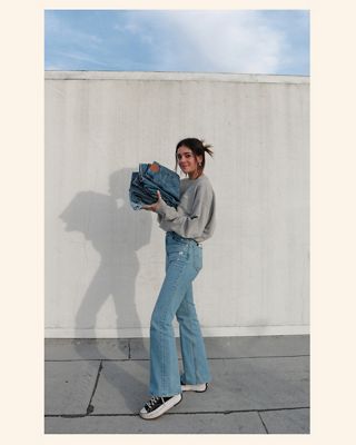 Luann standing with a stack of denim