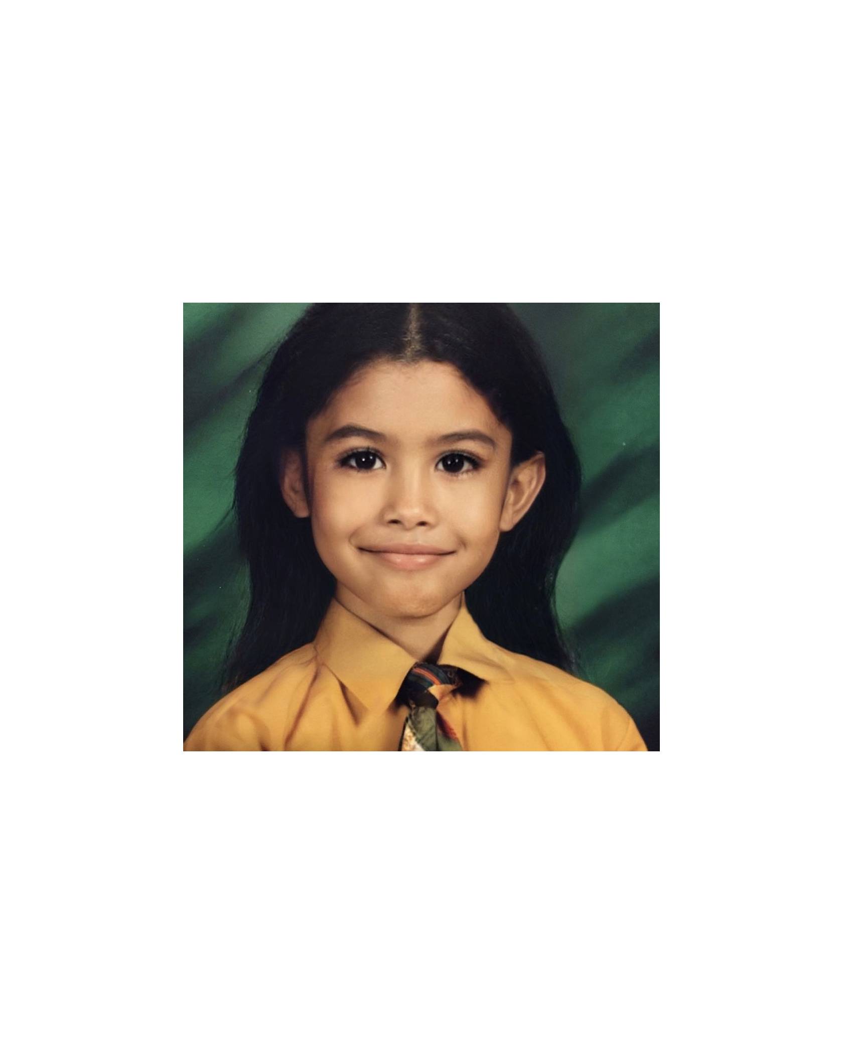A childhood photo of Leyna Bloom wearing an orange/yellow shirt and a colorful tie.