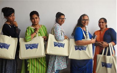 5 women standing with their tote bags