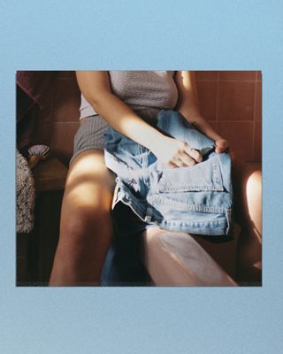 Close up photo of model holding pair of lightwash jeans with a light blue color panel on the left