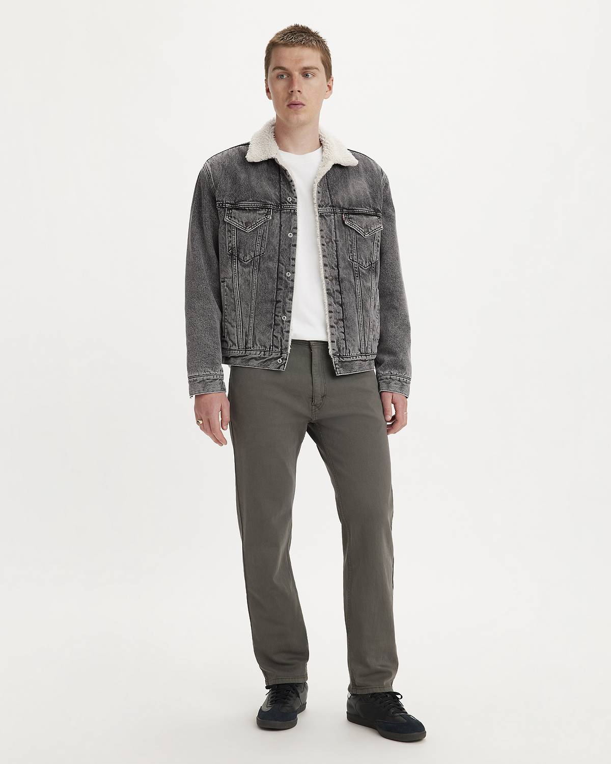 Model wearing dark wash pants with a trucker jacket of the same color and white top under.