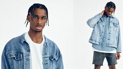 Shai wearing a denim jacket with white shirt looking down at the ground.