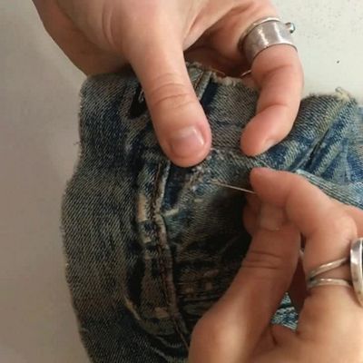 hand stitching up and down along hole on denim jeans