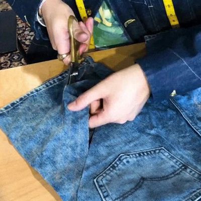 woman hands cutting denim strips with scissors