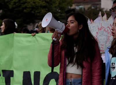 A photo of Xiye Bastida at a protest speaking into a megaphone.